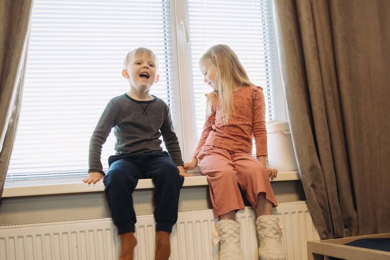 Kinder sitzen auf Heizung