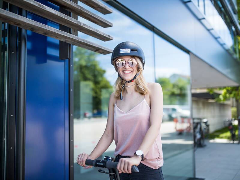 Eine fröhliche junge Frau mit Helm auf einem Segway