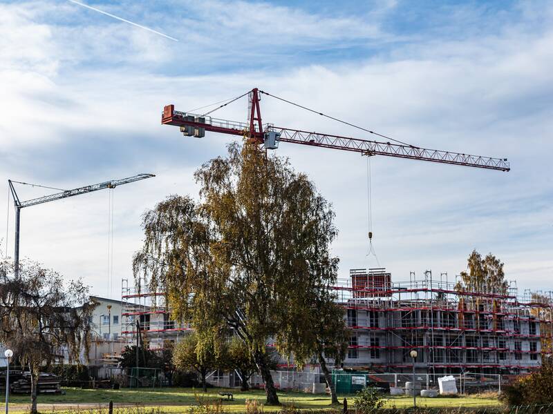 Zwei gelbe Baukräne bei einer Baustelle für ein Haus.